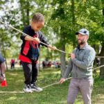 Man and kid crossing a rope bridge between trees in Bloomington, IN