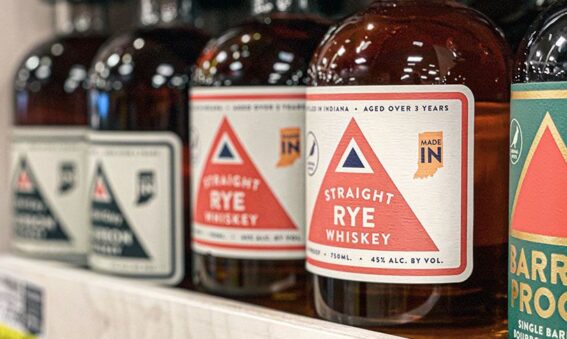 A row of rye whiskey bottles on a wooden shelf in Bloomington, IN